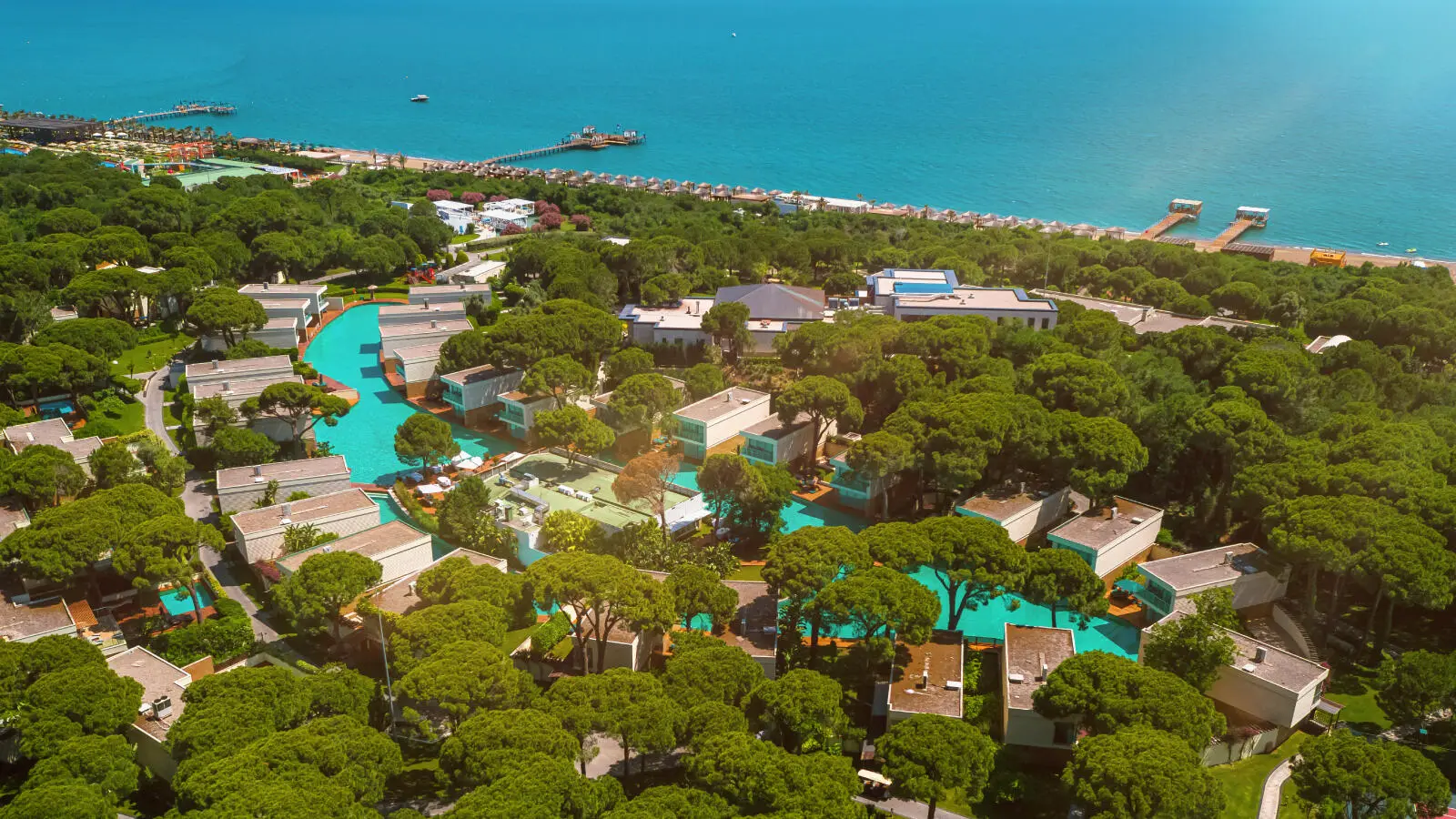 Vista aerea del Club Privé by Rixos Belek che mostra ville di lusso circondate da pini e piscine turchesi sul Mar Mediterraneo.