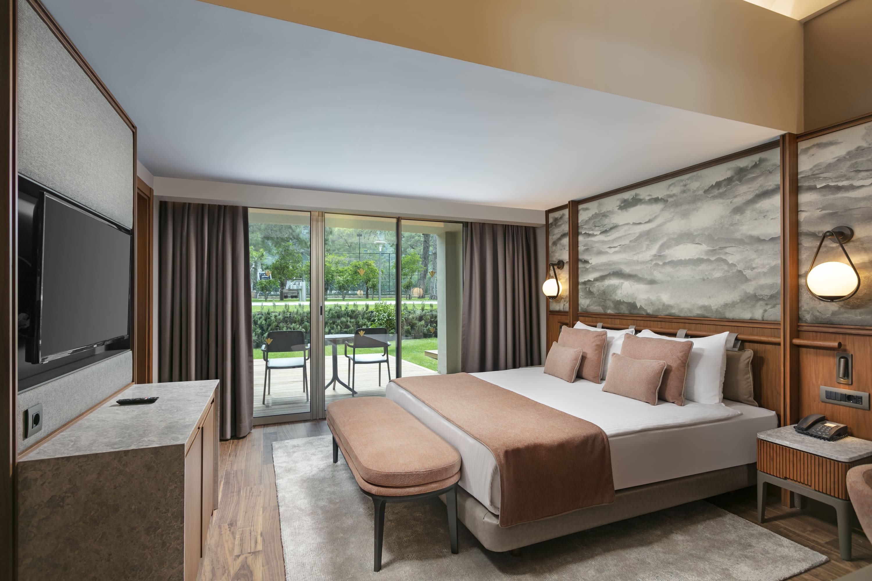 Spacious bedroom in the Marine Suite at Rixos Sungate. The room features a king-size bed with a cloud-patterned headboard, a makeup vanity with a tall mirror, and sliding doors opening directly to the garden terrace